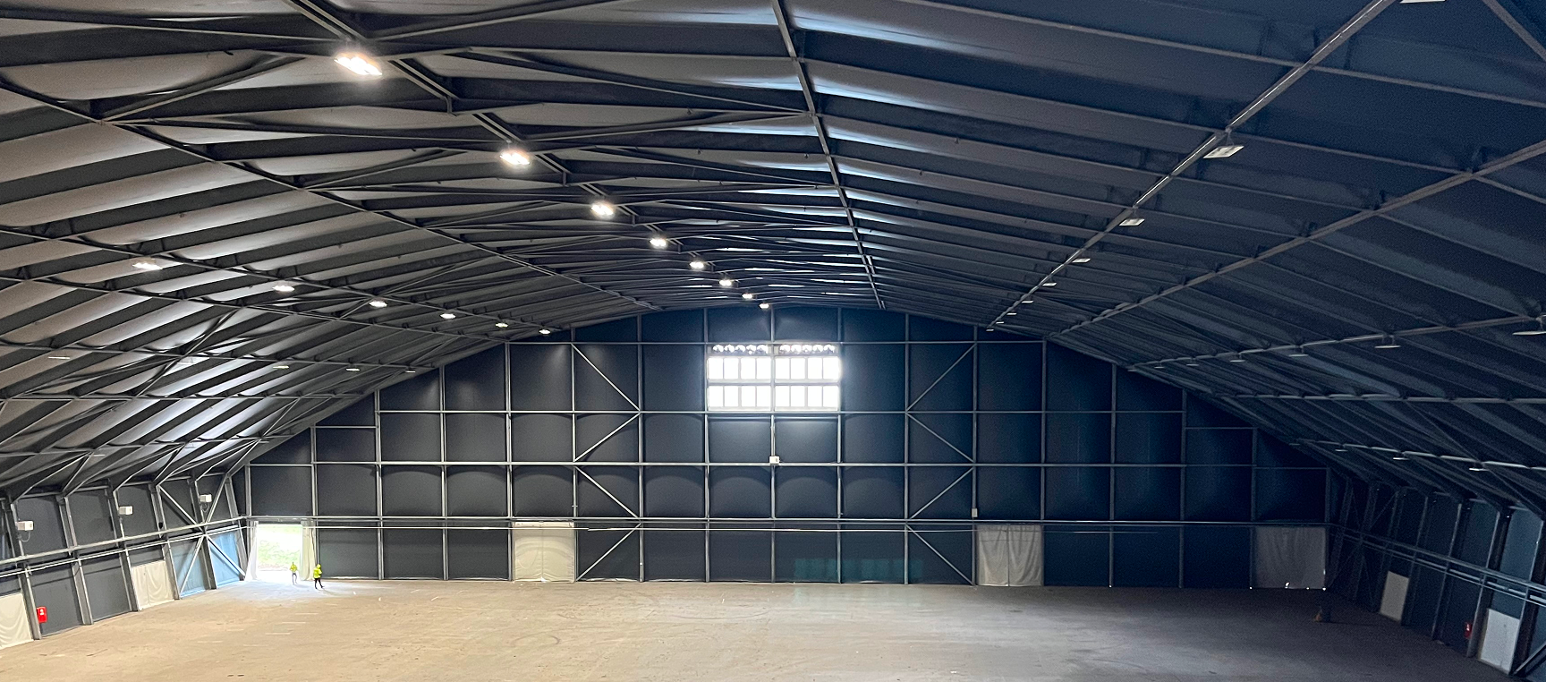 Innenraum einer großen Lagerhalle mit geschwungenem Stahlrahmen und Textilbespannung
