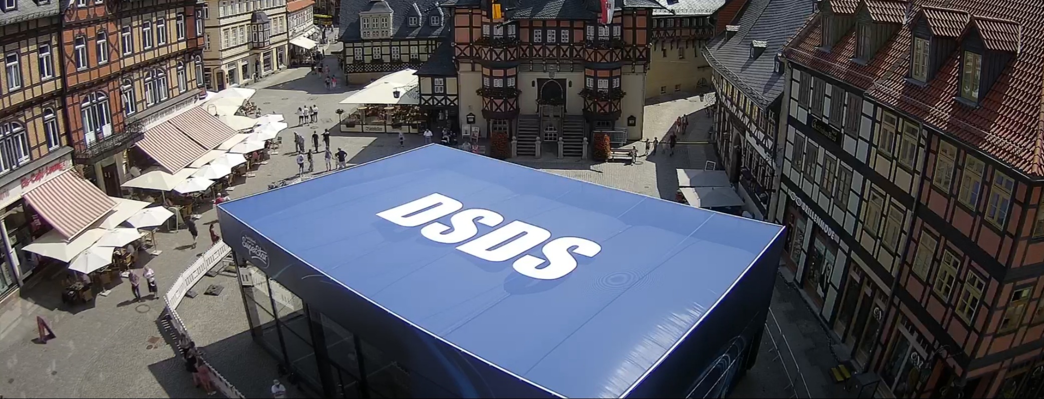 Luftaufnahme einer großen blauen DSDS-Textilkonstruktion auf einem historischen Stadtmarktplatz