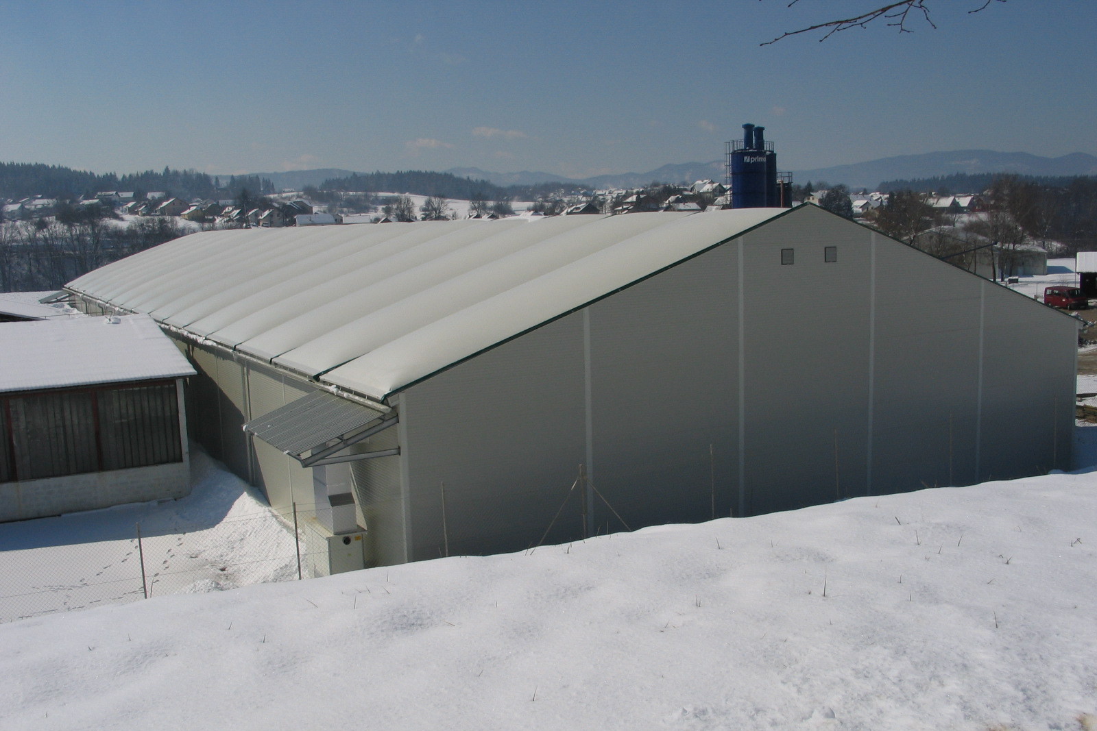 Außenansicht einer Lagerhalle mit Textilsatteldach im Schnee, ländliche Umgebung
