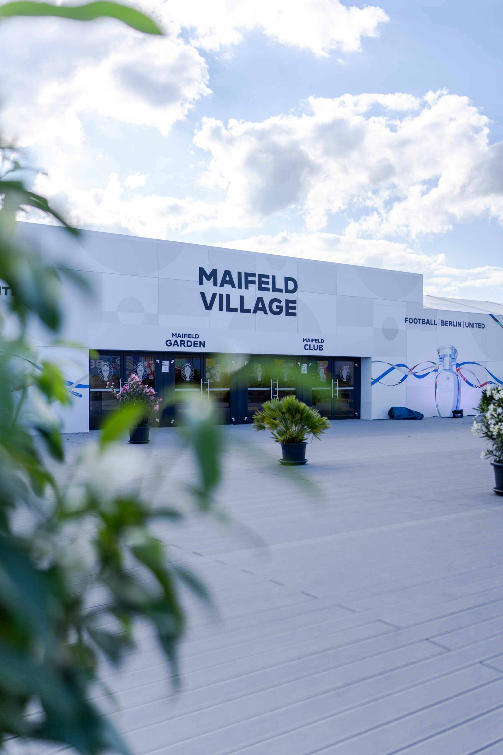 Eingangsbereich des Maifeld Village während UEFA EURO 2024 mit Textilgebäude und Bepflanzung