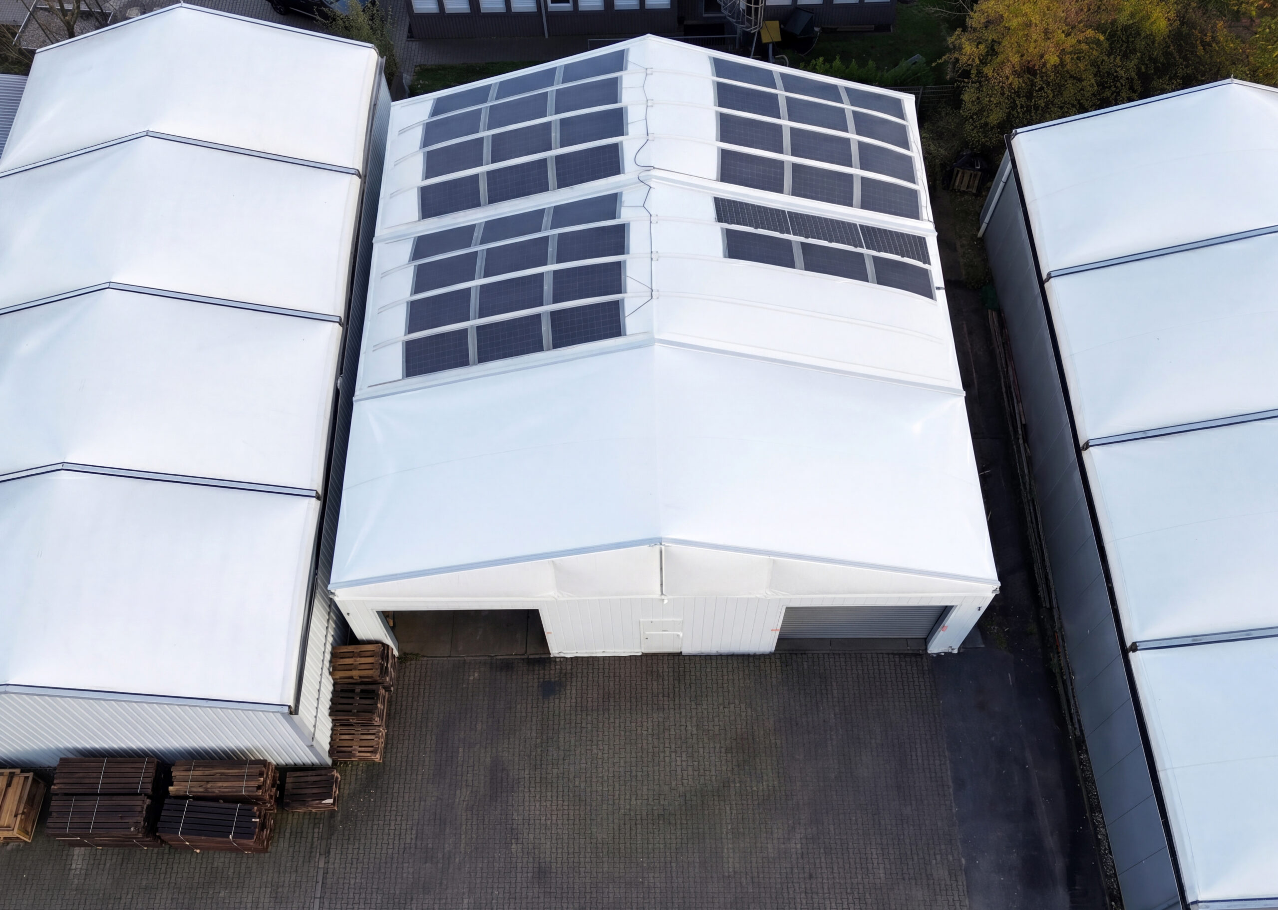 Vogelperspektive auf drei Textilhallen mit integrierter Solarplane auf dem Dach der mittleren Halle