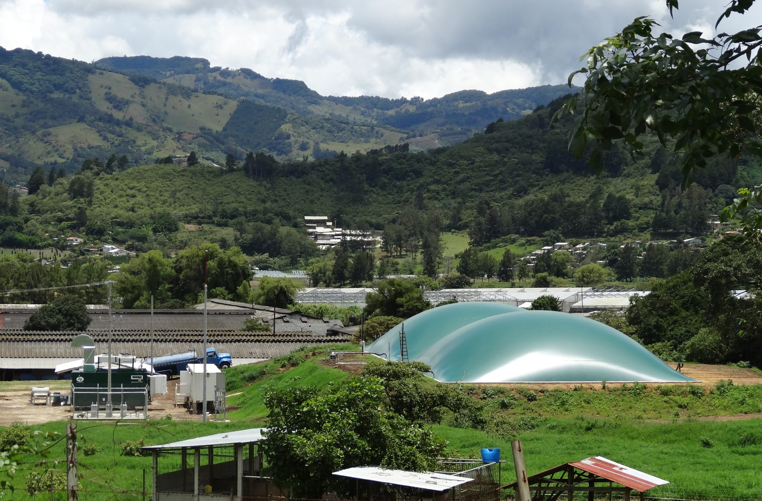 Biogasanlage mit grüner Membrankuppel in bergiger Landschaft
